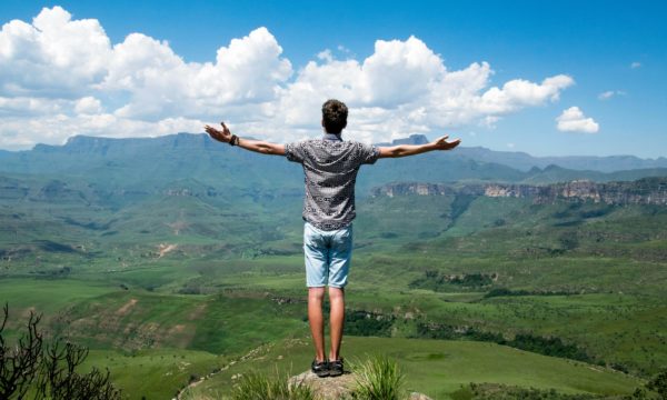 un homme bras ouvert face à un paysage de montagne