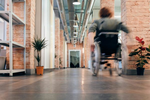 femme qui déambule en fauteuil roulant dans une entreprise